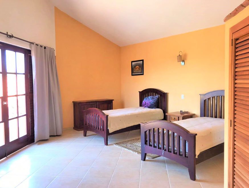 buyDRproperty Two beds in a beautiful 5 bedroom villa bedroom with orange walls. Sosua Real Estate