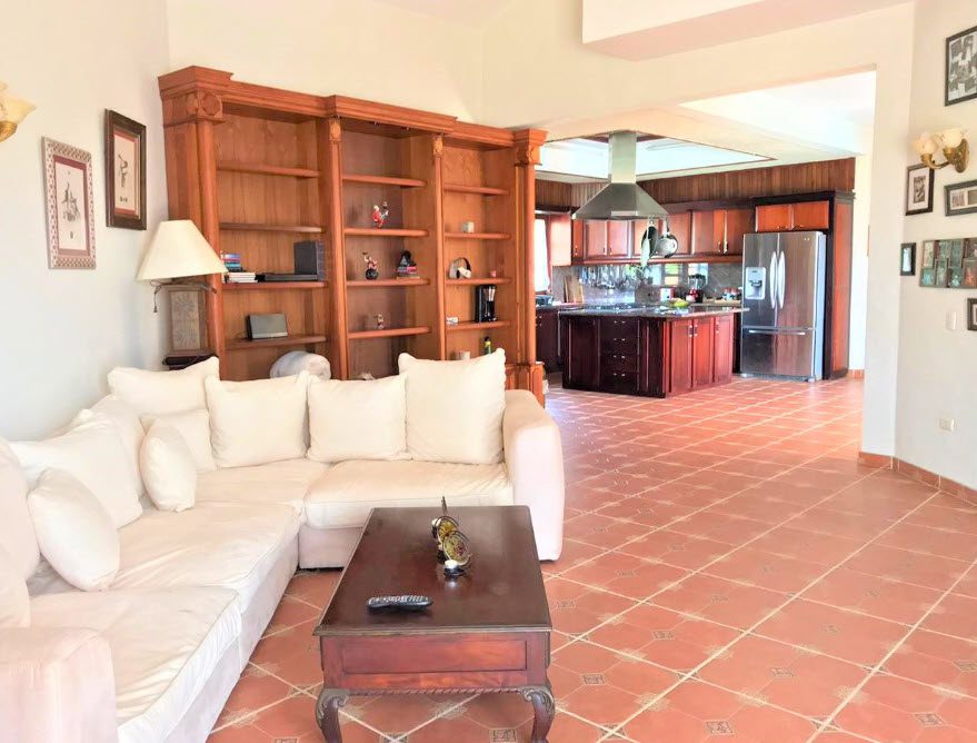 buyDRproperty Living room with white sofa, bookshelves, and view into the kitchen of a beautiful 5 bedroom villa. Sosua Real Estate