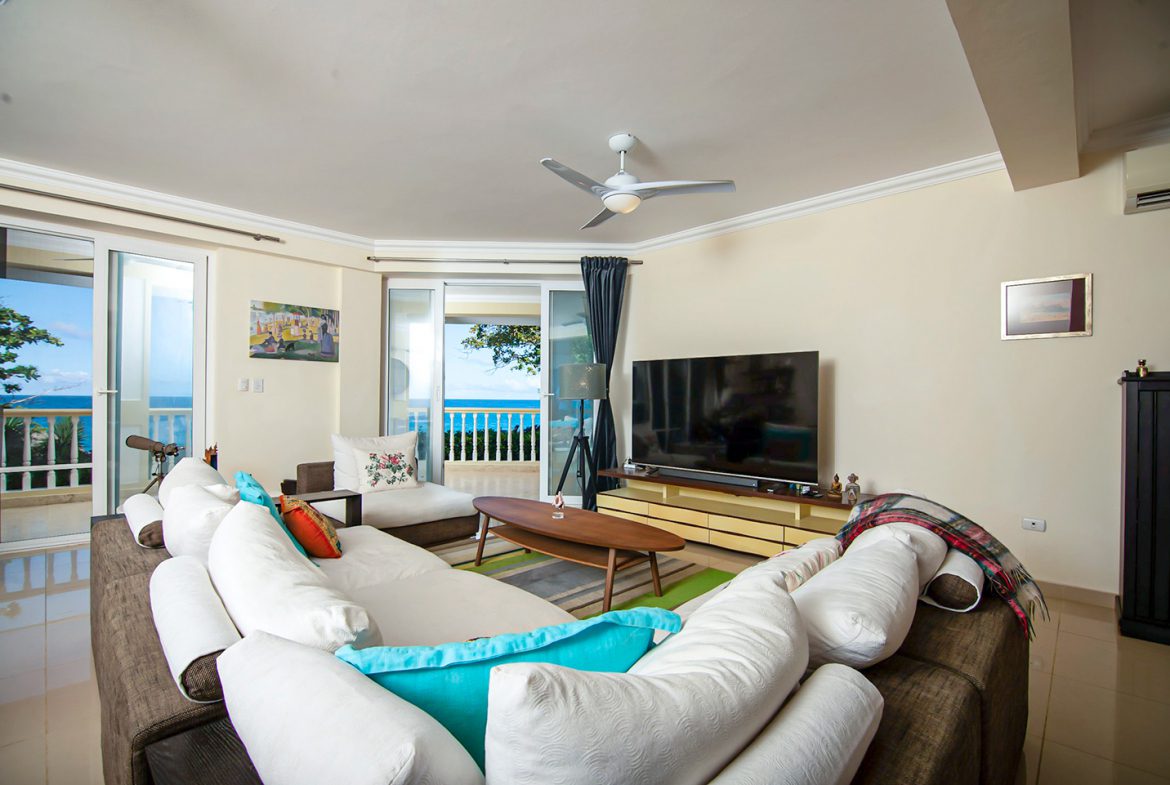 buyDRproperty Living room of an oceanfront condo in Sosua with ocean view and comfortable seating. Sosua Real Estate