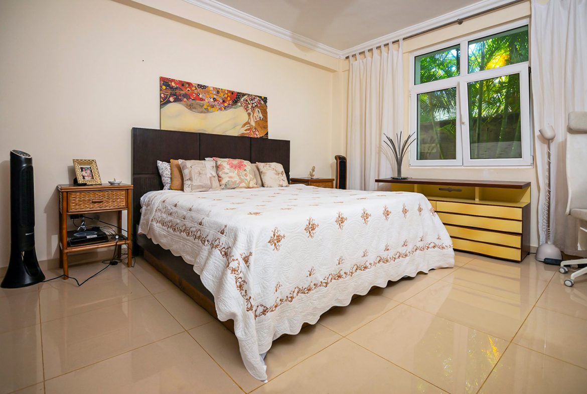 buyDRproperty Bedroom in oceanfront condo in Sosua with bed, nightstand, and art. Sosua Real Estate