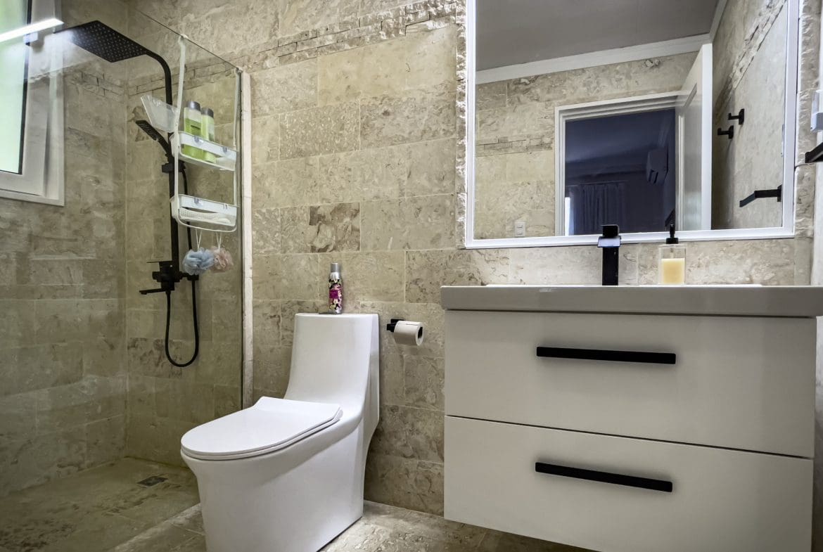 buyDRproperty Modern bathroom with a walk-in shower, toilet, and vanity. Features of the 3 Bedroom Oceanfront Condo in Sosua. Sosua Real Estate