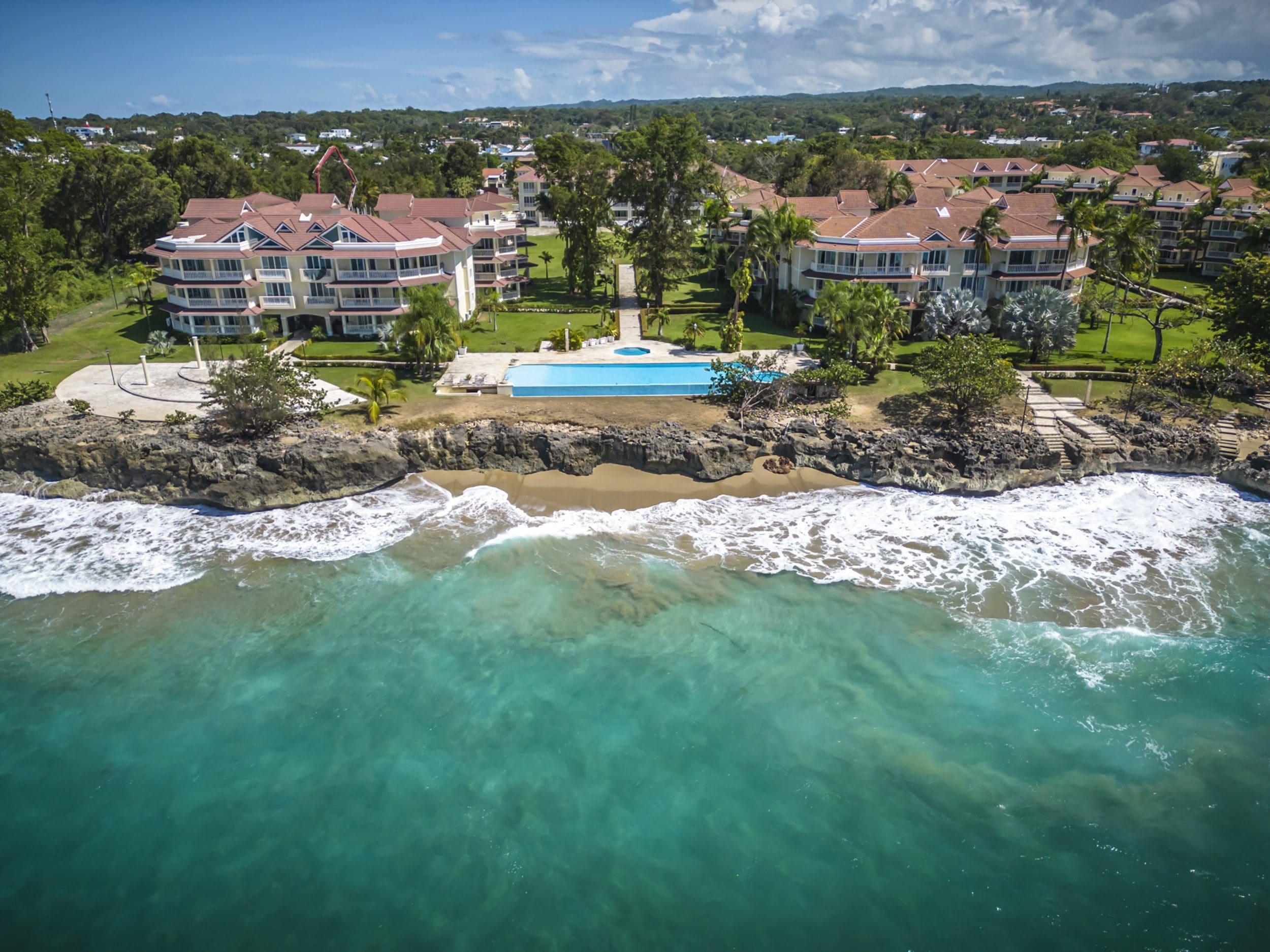 buyDRproperty Aerial view of a 3 bedroom oceanfront condo for sale in Sosua with a turquoise ocean and a swimming pool Sosua Real Estate