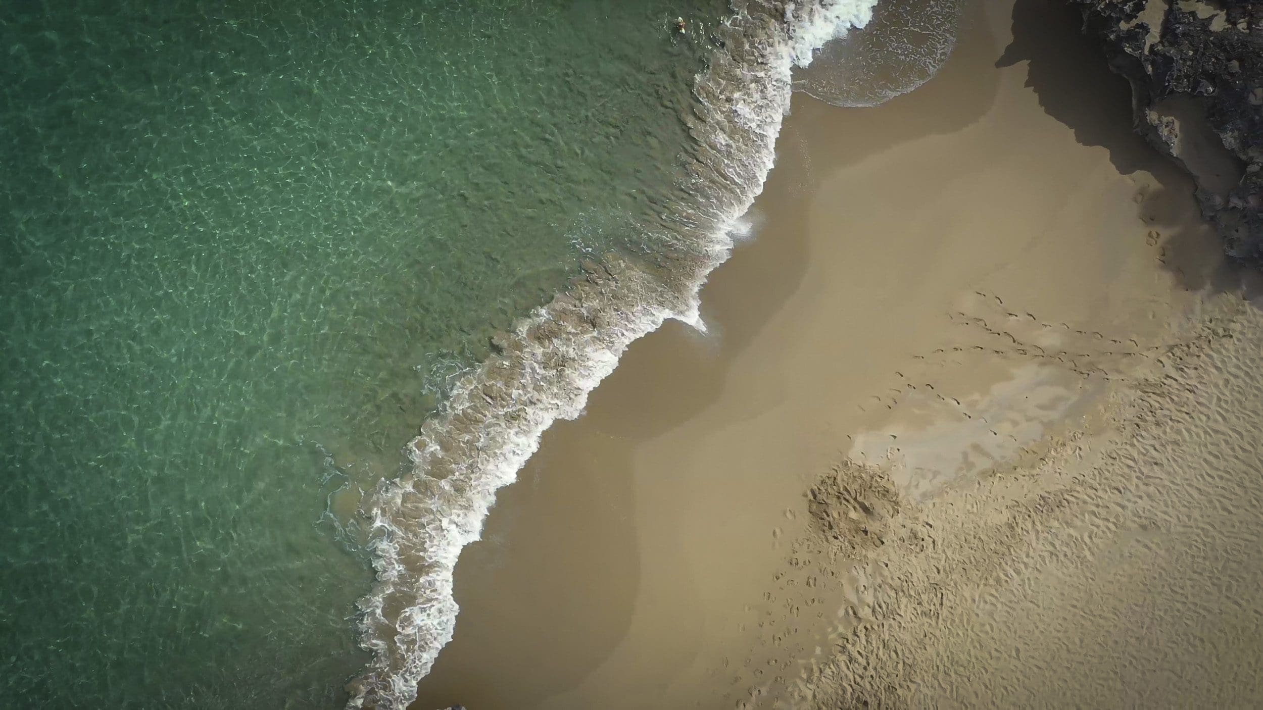 buyDRproperty Aerial view of a beach with turquoise water and waves, perfect for a 3 Bedroom Oceanfront Condo. Sosua Real Estate