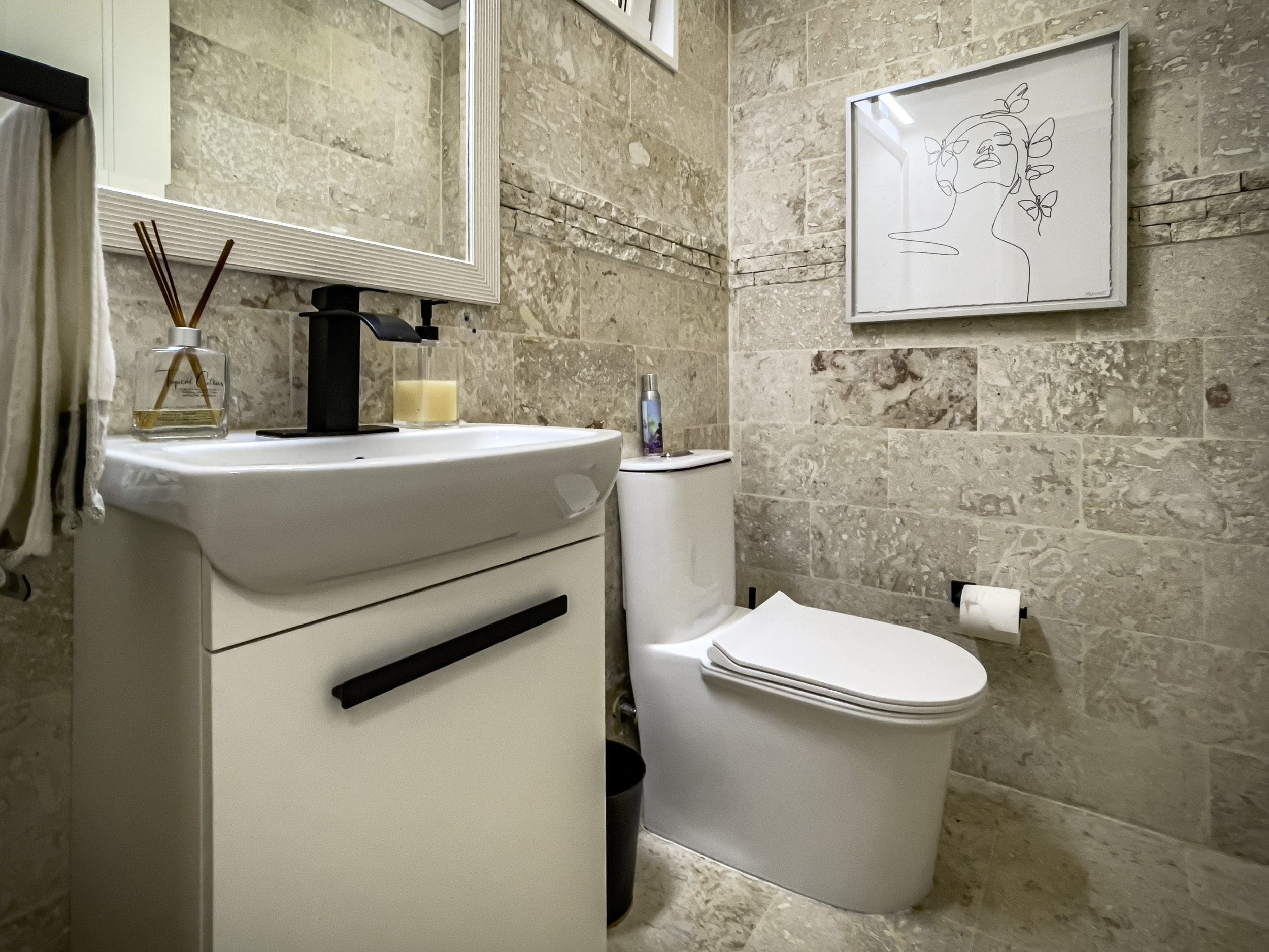 buyDRproperty Modern bathroom with a white sink, toilet, and stone-like tile. 3 Bedroom Oceanfront Condo Sosua Real Estate