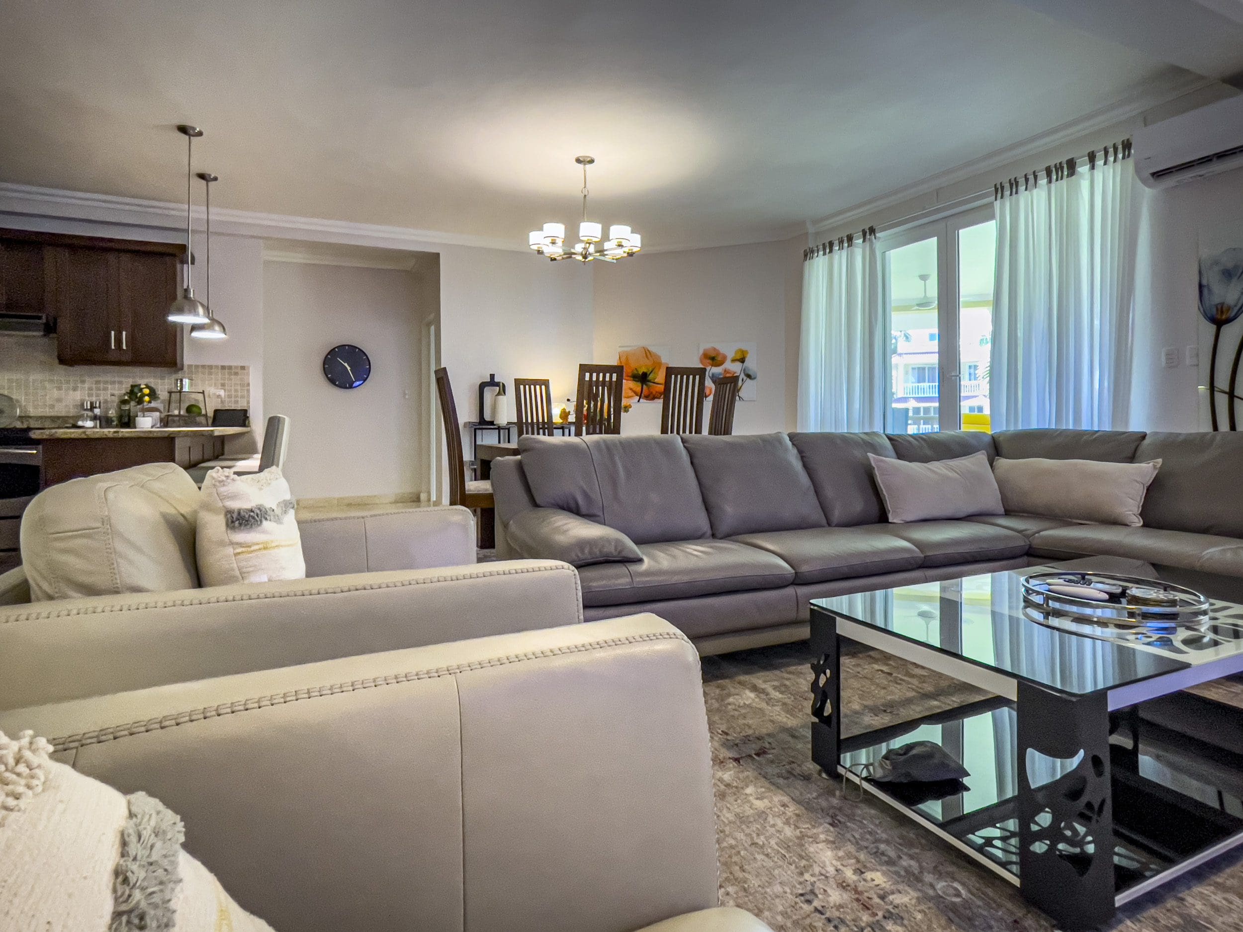 buyDRproperty Living room of a 3 Bedroom Oceanfront Condo in Sosua with grey leather sofa and glass coffee table. Sosua Real Estate