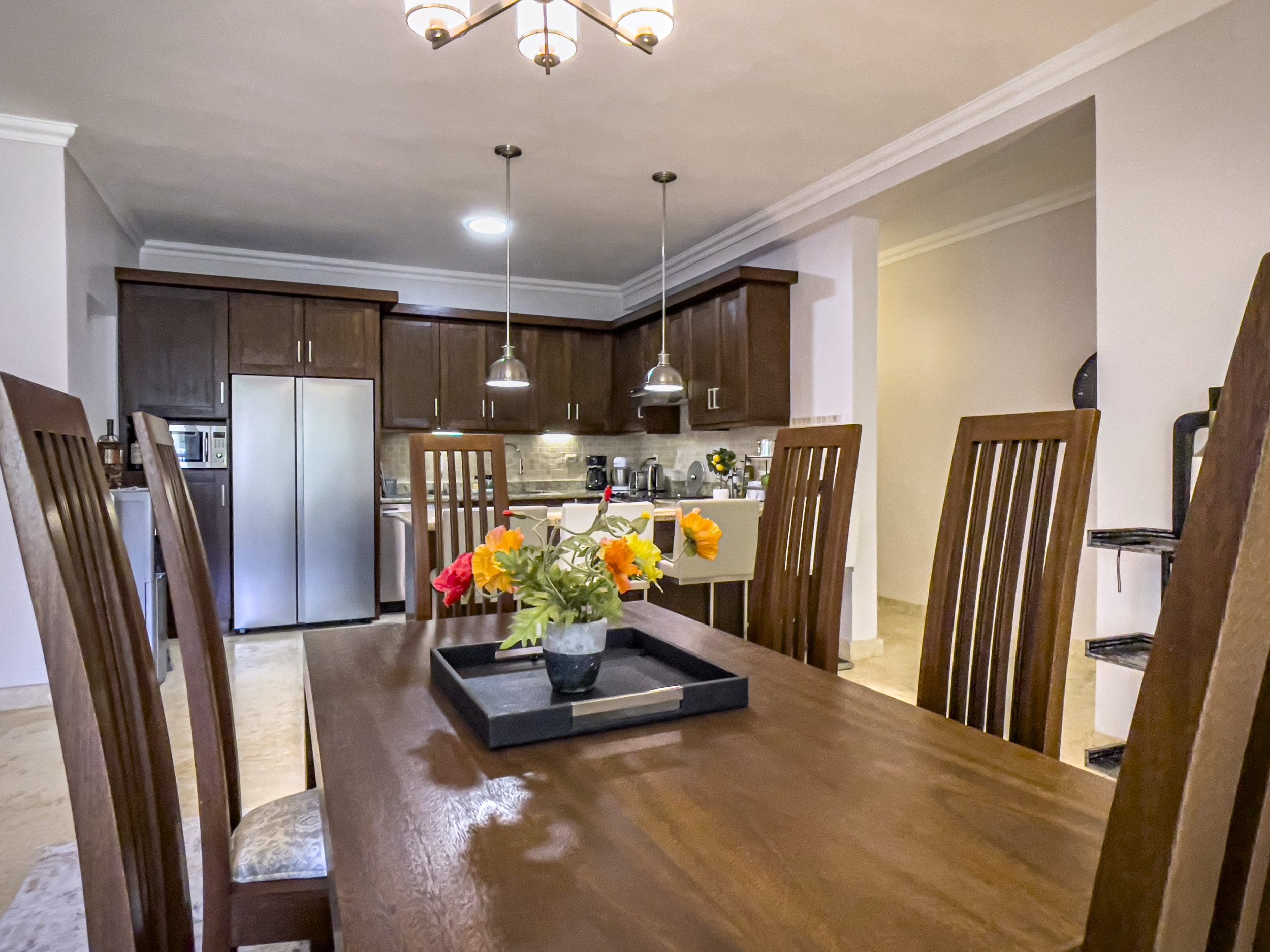 buyDRproperty Dining room with a wooden table and chairs, leading to the kitchen in a 3 Bedroom Oceanfront Condo. Sosua Real Estate
