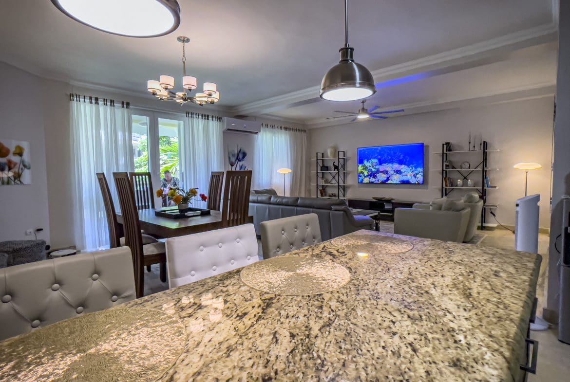 buyDRproperty Open-concept living area in a 3 bedroom oceanfront condo, featuring a kitchen island and dining area. Sosua Real Estate