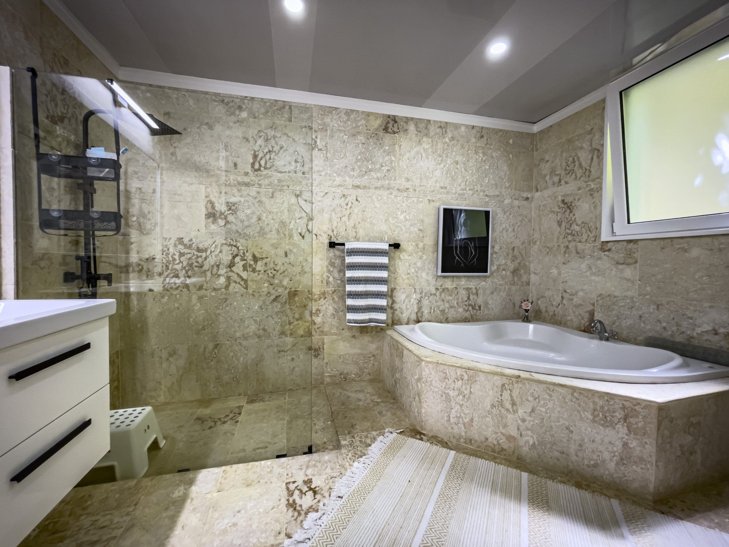 buyDRproperty Bathroom with stone tiles, bathtub, and shower. Sosua Real Estate