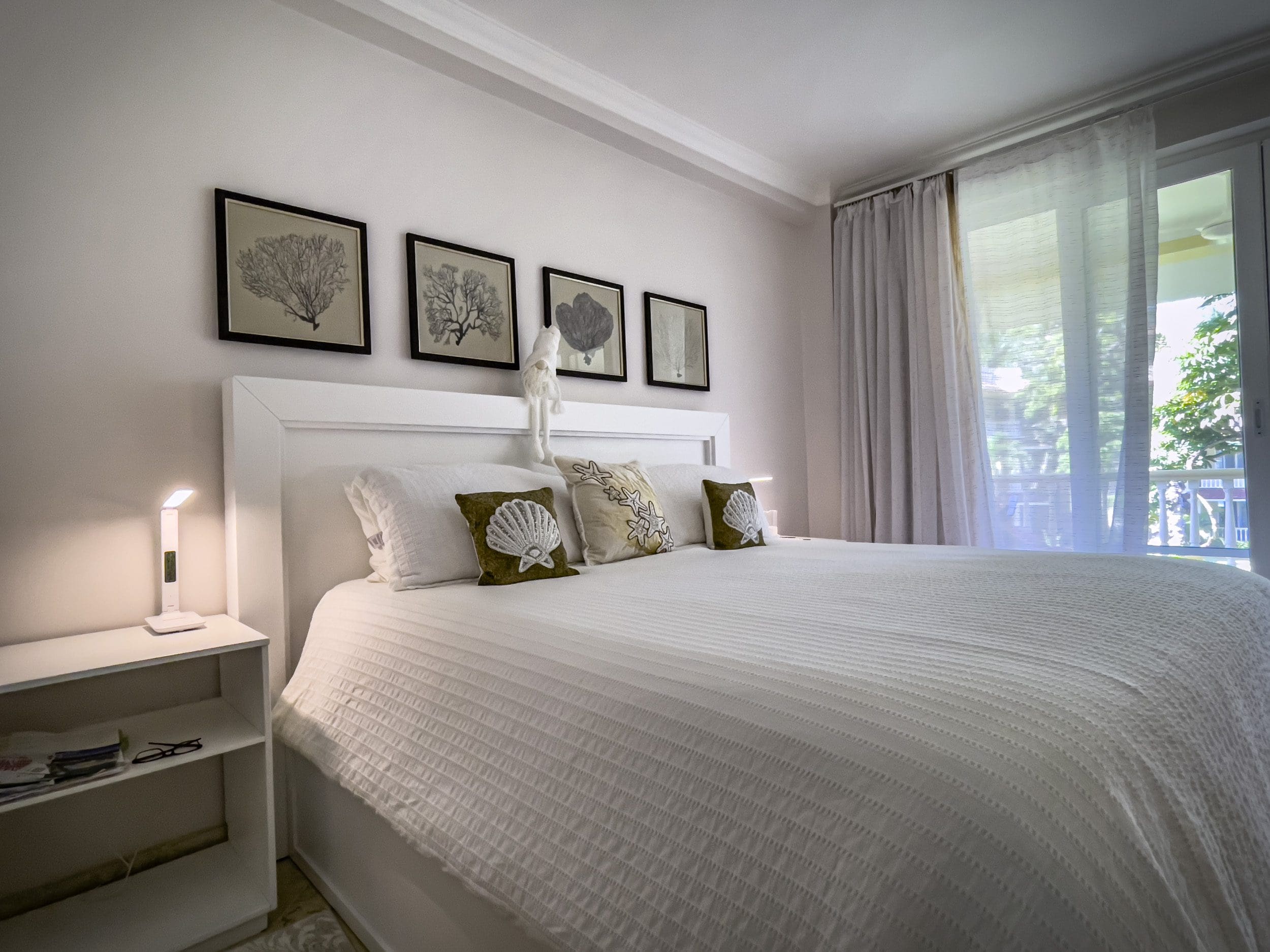 buyDRproperty Bedroom in a 3 Bedroom Oceanfront Condo with white bed and seashell pillows. Sosua Real Estate