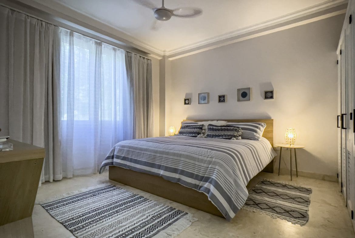 buyDRproperty Coastal bedroom with a striped comforter, rugs, and a 3 bedroom oceanfront condo feel. Sosua Real Estate