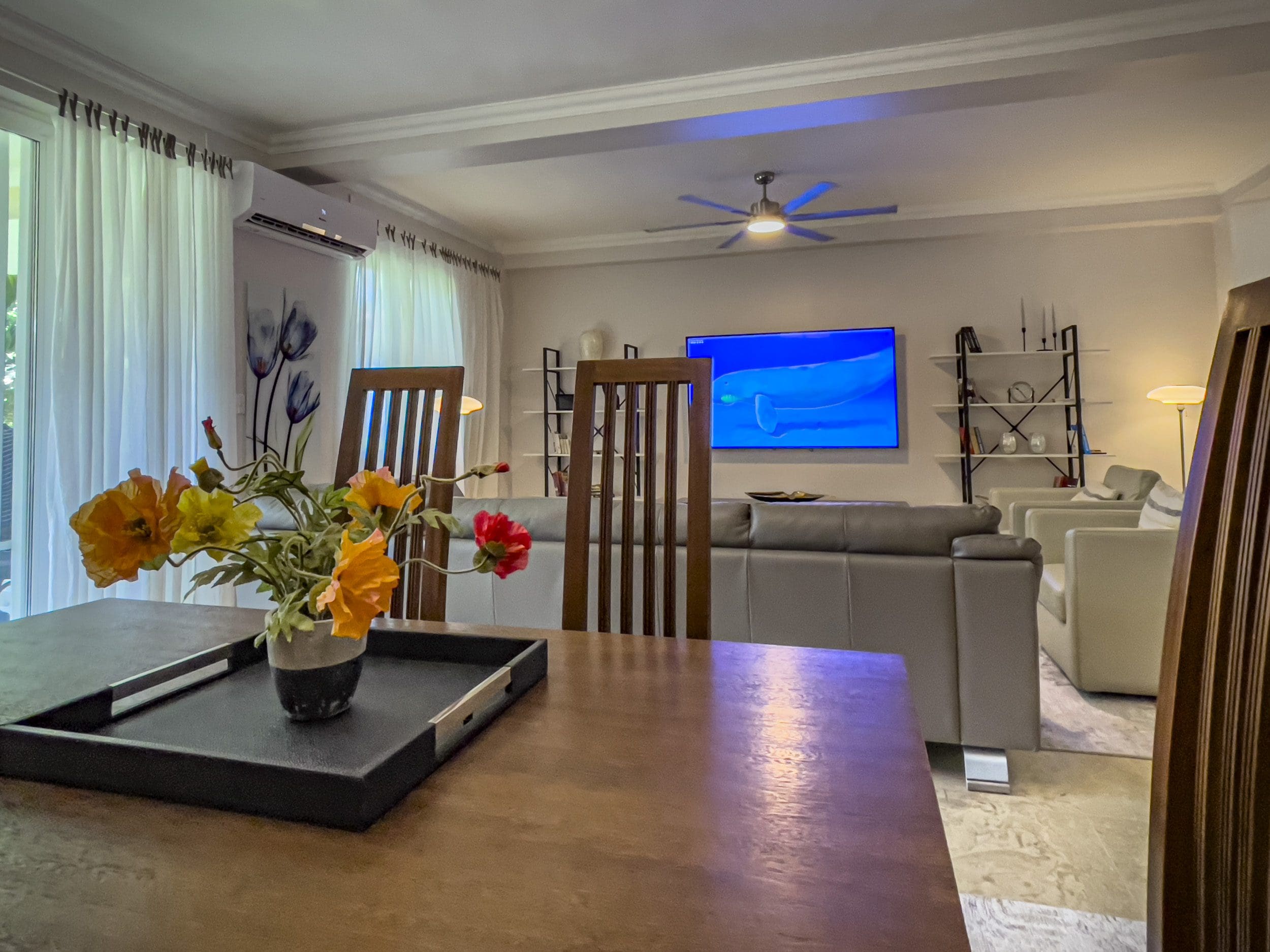 buyDRproperty Dining area of a 3 bedroom oceanfront condo with flowers and TV Sosua Real Estate