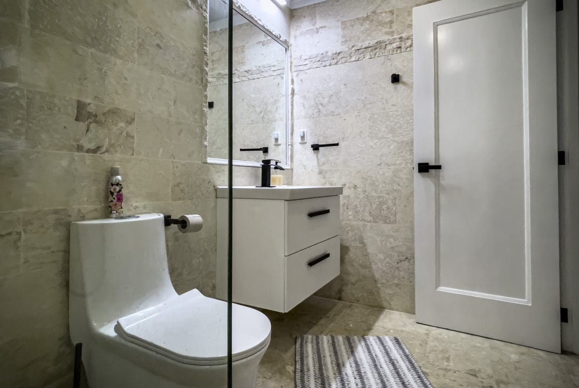 buyDRproperty Modern bathroom with white vanity, toilet, and tile. Features black hardware. Sosua Real Estate