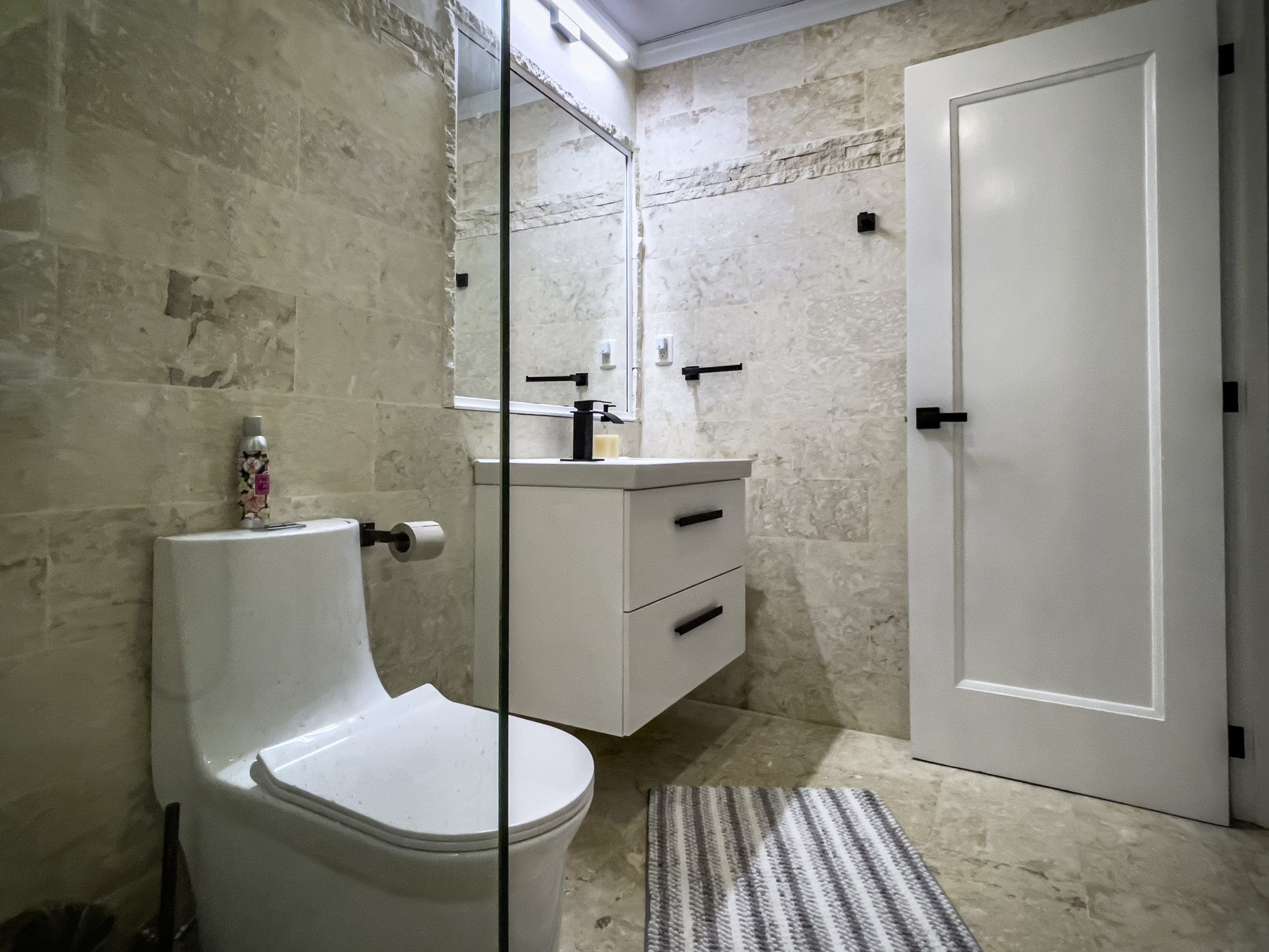 buyDRproperty Modern bathroom with white vanity, toilet, and tile. Features black hardware. Sosua Real Estate