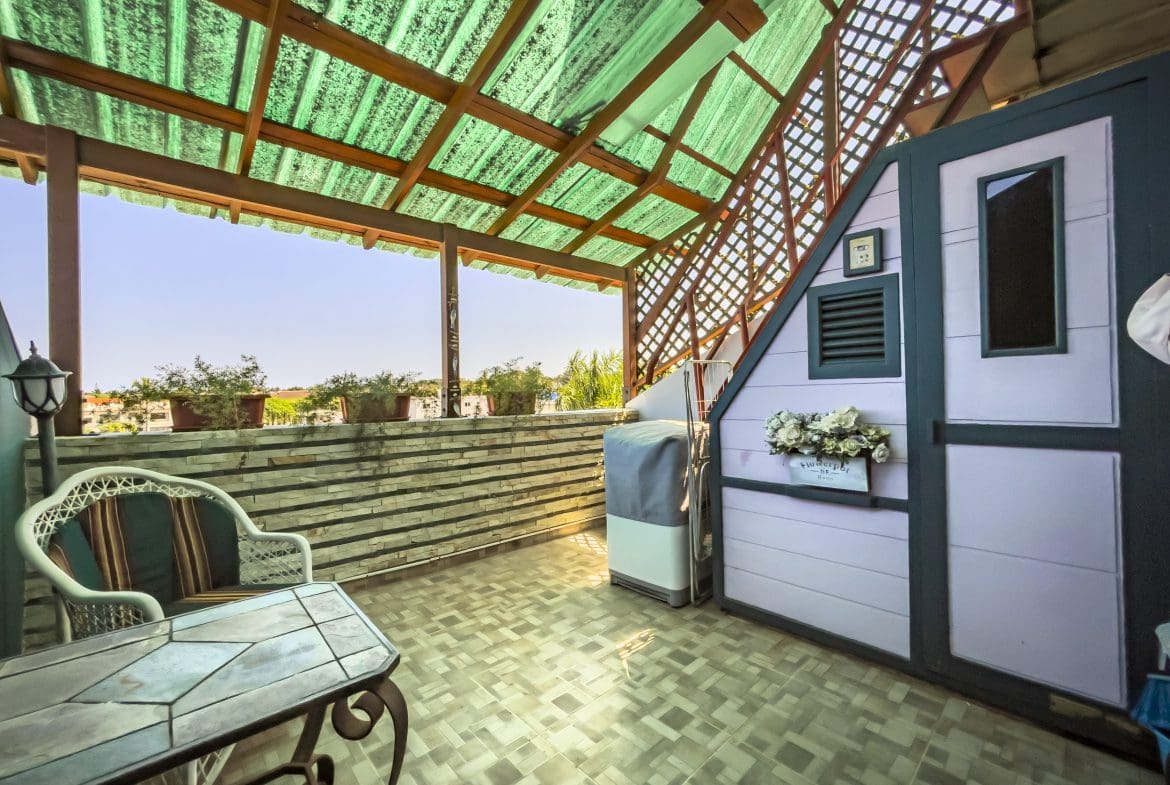 buyDRproperty Outdoor patio of a 2-bedroom condo in the heart of Sosua, with table, chair, and view. Sosua Real Estate