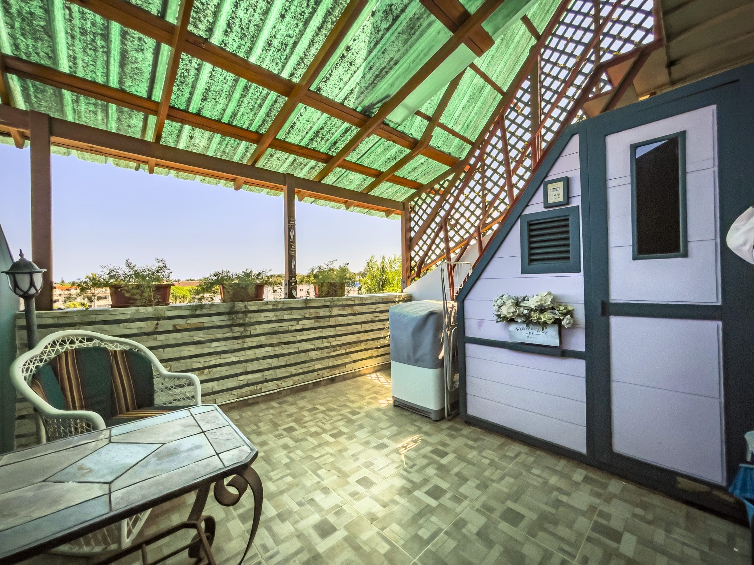 buyDRproperty Outdoor patio of a 2-bedroom condo in the heart of Sosua, with table, chair, and view. Sosua Real Estate