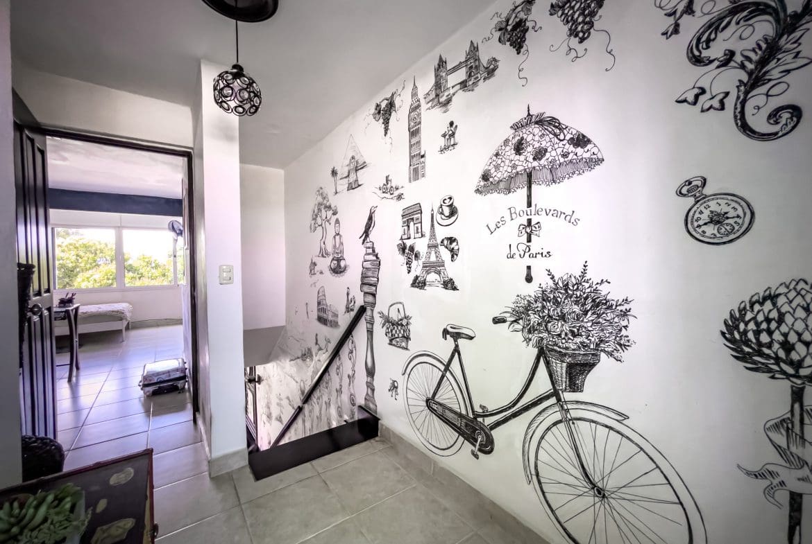 buyDRproperty Hallway with Paris-themed mural, leading to a 2-bedroom condo in Sosua. Sosua Real Estate