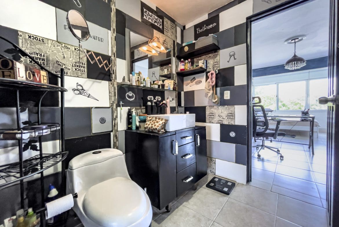 buyDRproperty Bathroom with artistic tile design, featuring black vanity and white toilet. Sosua Real Estate