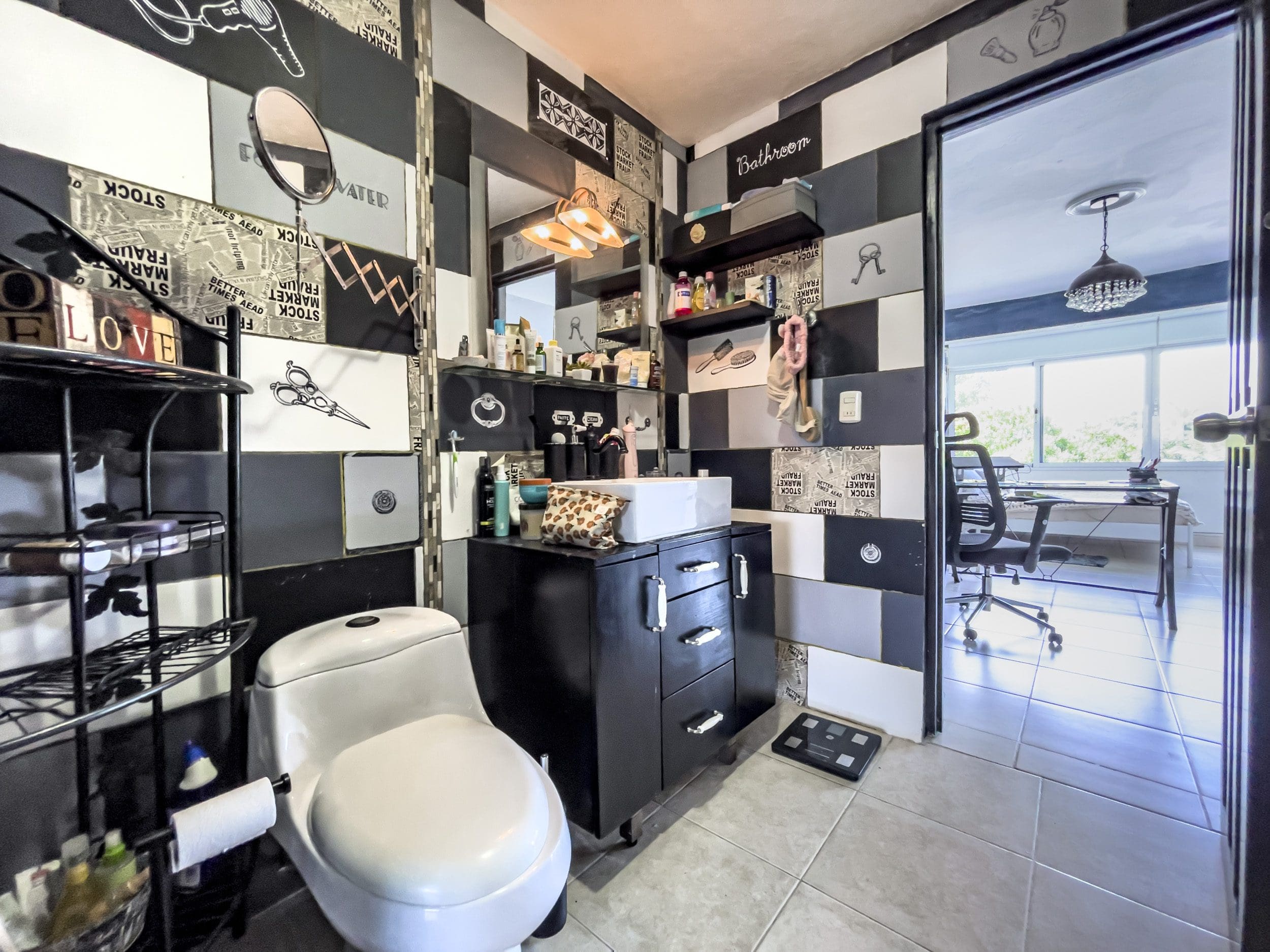 buyDRproperty Bathroom with artistic tile design, featuring black vanity and white toilet. Sosua Real Estate