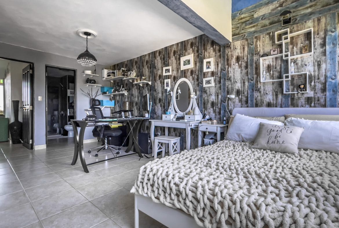 buyDRproperty Bedroom in a 2-bedroom condo in Sosua with a cozy bed and vanity. Sosua Real Estate