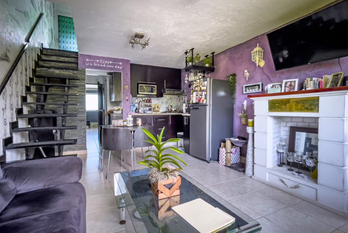 buyDRproperty Living room of a 2 bedroom condo in the heart of Sosua, featuring a fireplace and modern staircase. Sosua Real Estate