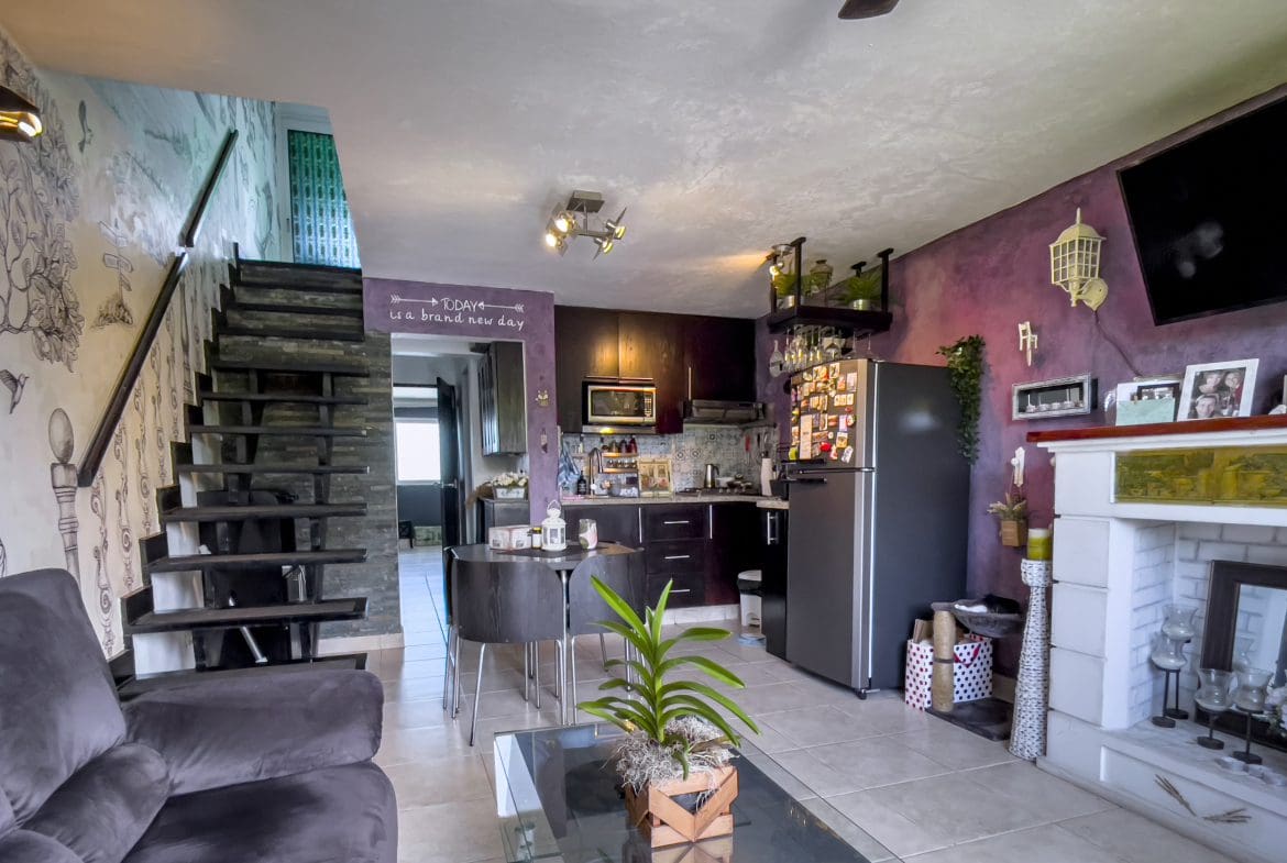 buyDRproperty Living room of a 2 bedroom condo in the heart of Sosua with stairs, kitchen, and fireplace. Sosua Real Estate