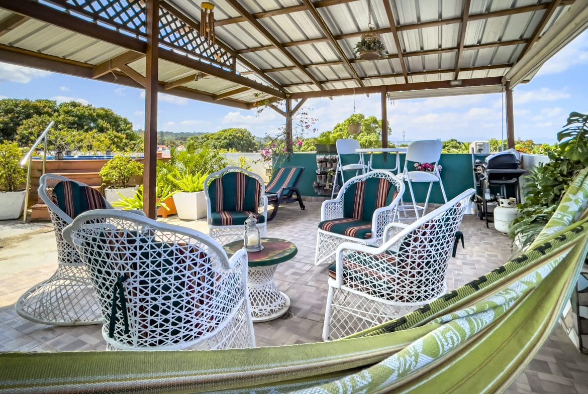 buyDRproperty Rooftop patio with white wicker furniture and hammock, perfect for a 2 bedroom condo in the heart of Sosua. Sosua Real Estate