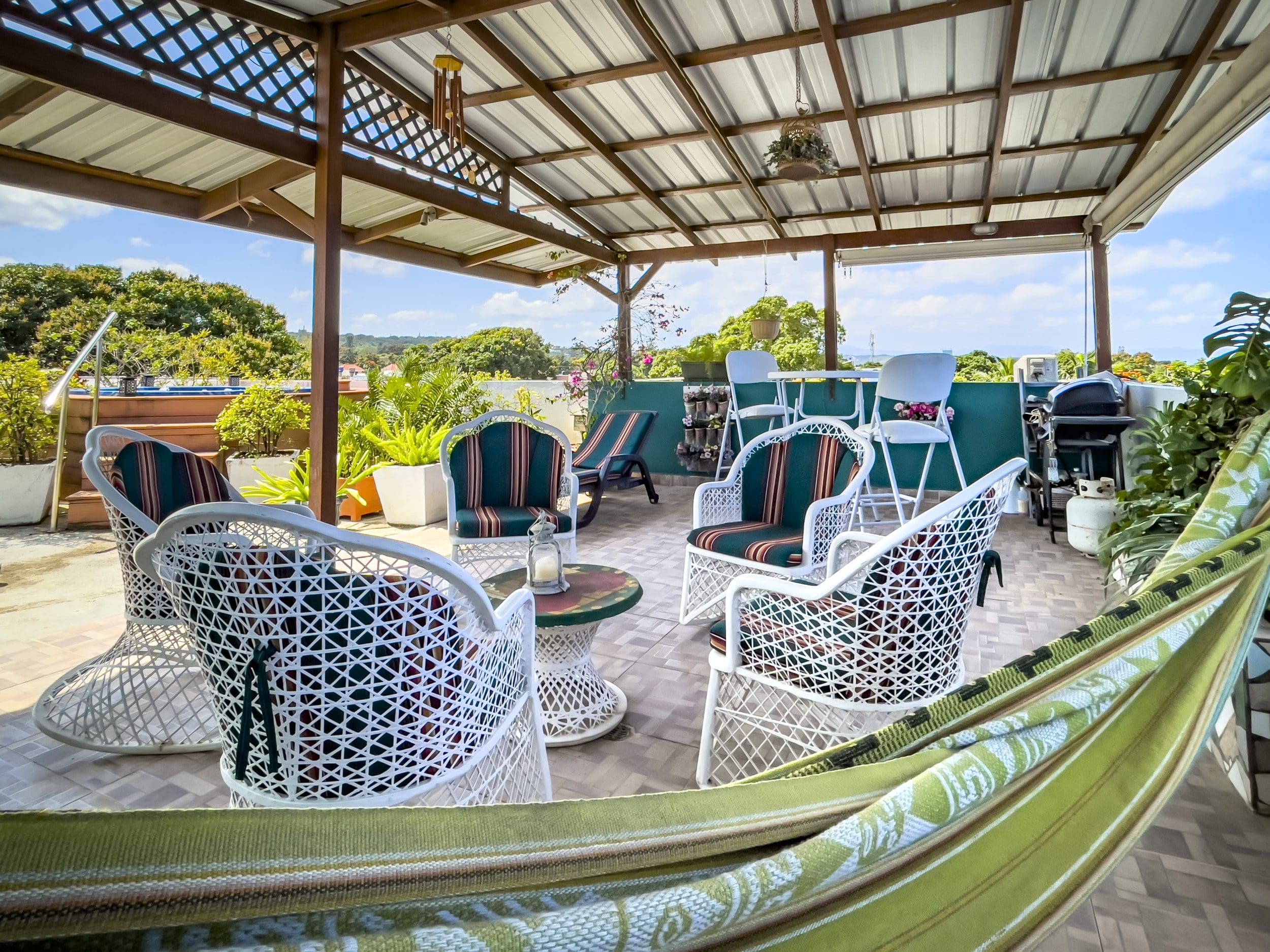 buyDRproperty Rooftop patio with white wicker furniture and hammock, perfect for a 2 bedroom condo in the heart of Sosua. Sosua Real Estate
