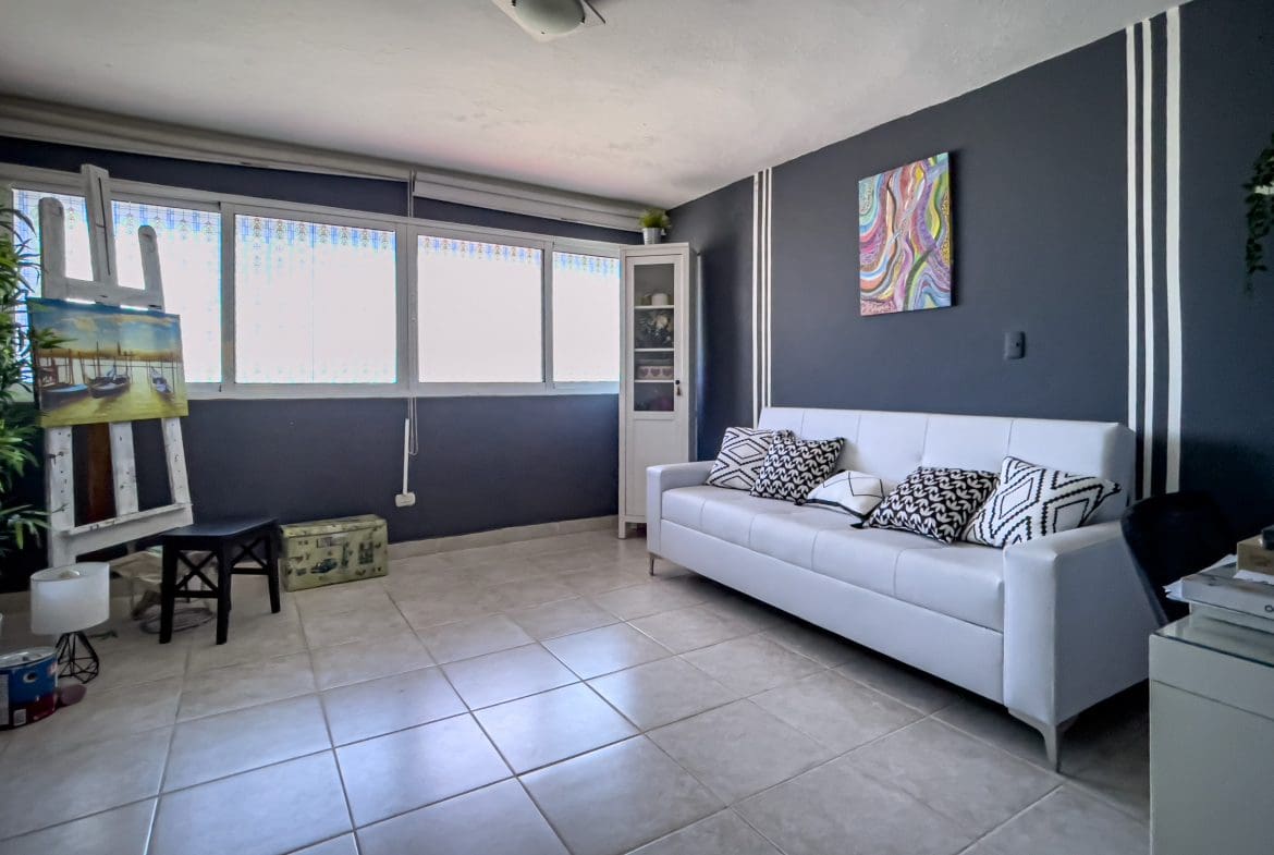 buyDRproperty Living room of a 2 Bedroom Condo in the heart of Sosua with white sofa and art. Sosua Real Estate