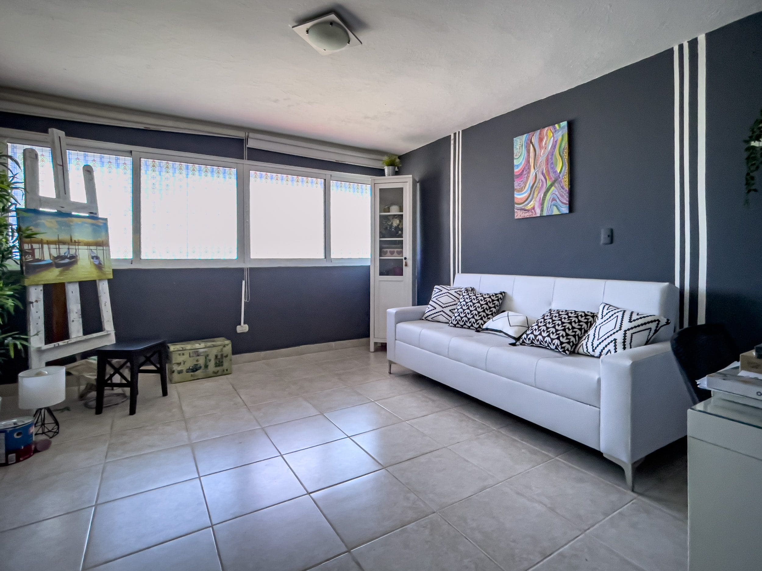 buyDRproperty Living room of a 2 Bedroom Condo in the heart of Sosua with white sofa and art. Sosua Real Estate