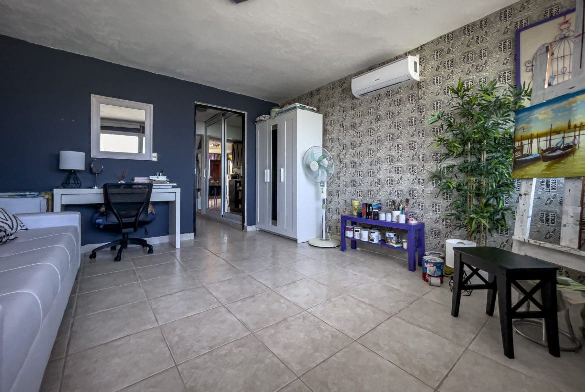 buyDRproperty Spacious 2-bedroom condo living area in Sosua, featuring a desk, sofa, and decorative plant. Sosua Real Estate