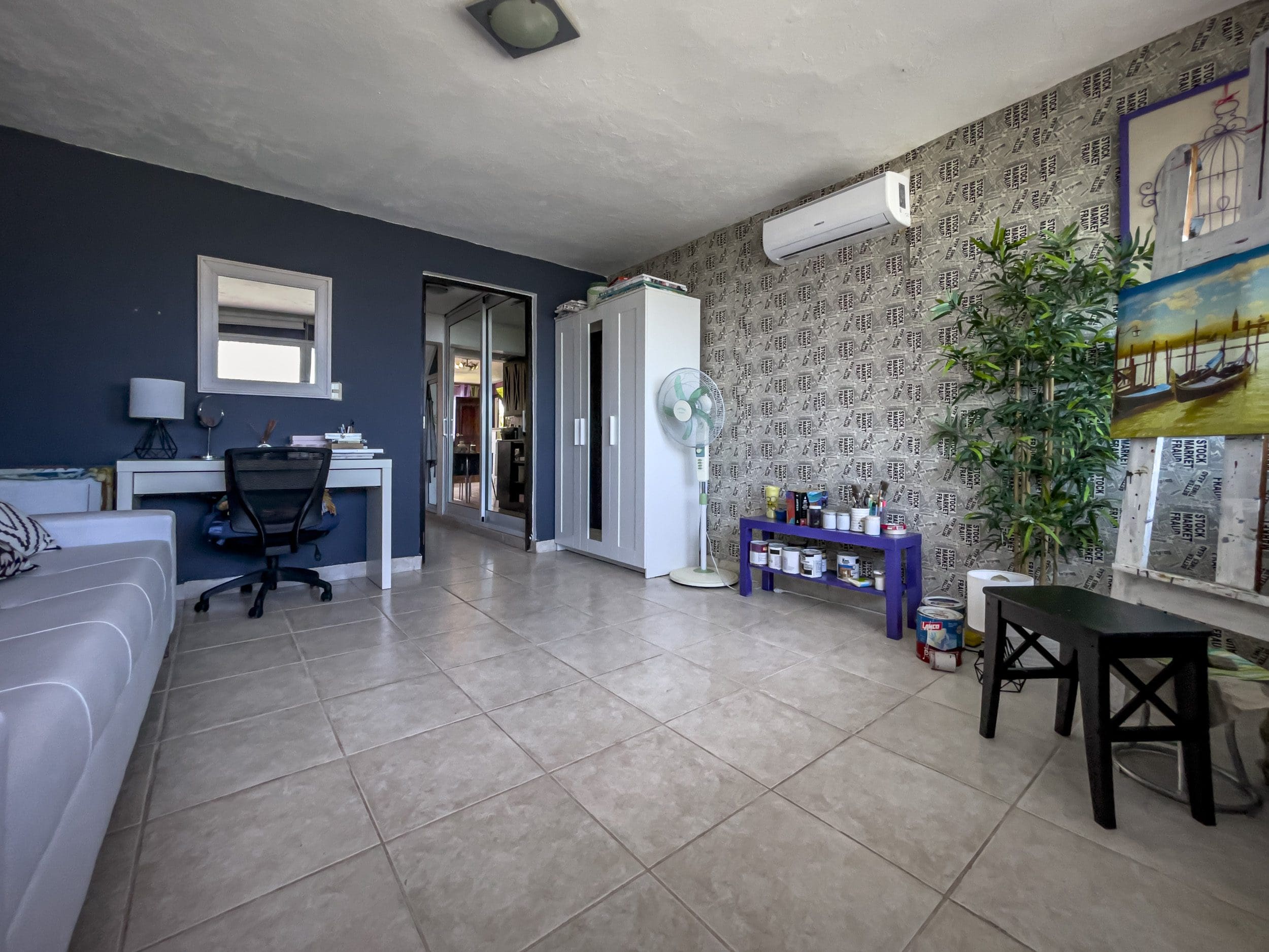 buyDRproperty Spacious 2-bedroom condo living area in Sosua, featuring a desk, sofa, and decorative plant. Sosua Real Estate