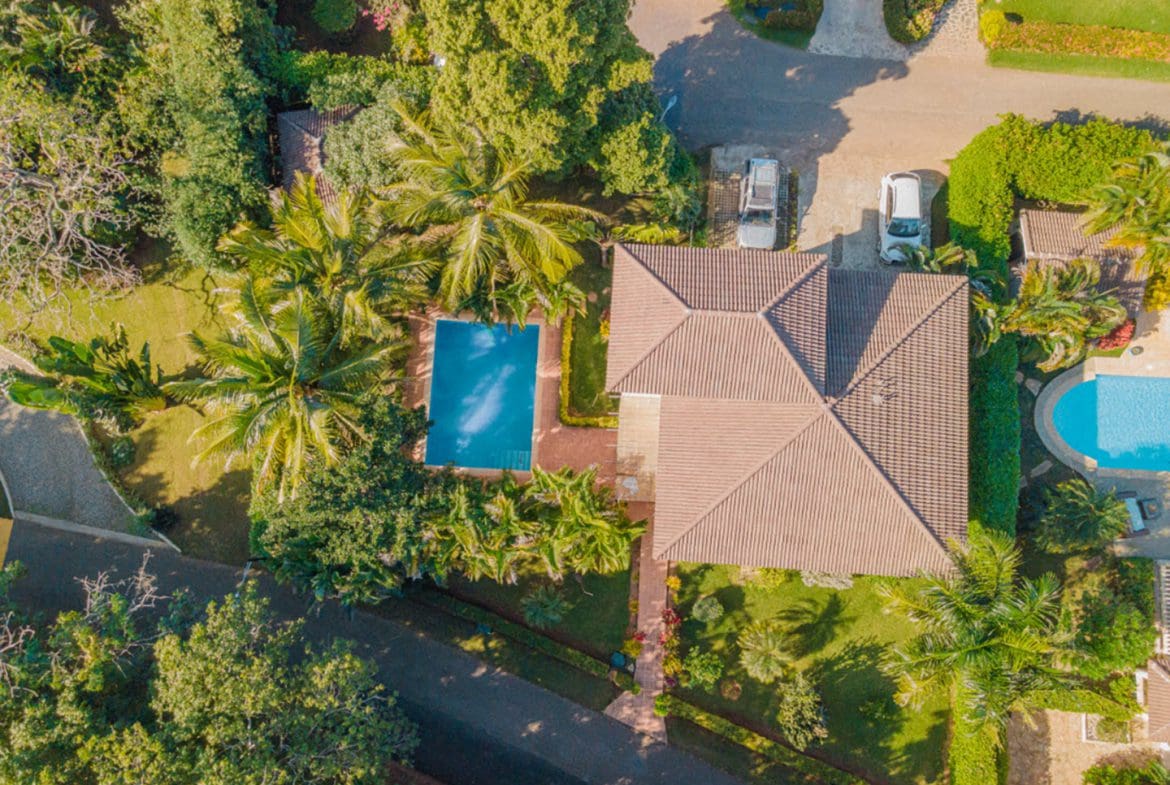 buyDRproperty Aerial view of a Hispaniola Two Unit Villa with a pool, trees, and a driveway. Residential Hispaniola. Sosua Real Estate