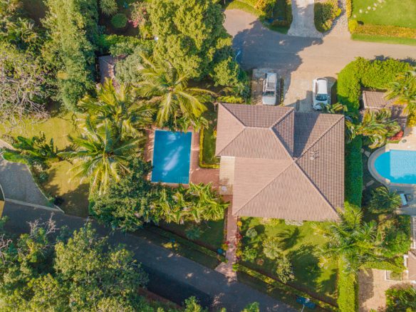 buyDRproperty Aerial view of a Hispaniola Two Unit Villa with a pool, trees, and a driveway. Residential Hispaniola. Sosua Real Estate