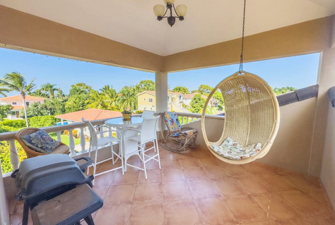 buyDRproperty Balcony of a Hispaniola Two Unit Villa with seating, hanging chair, and grill. Sosua Real Estate