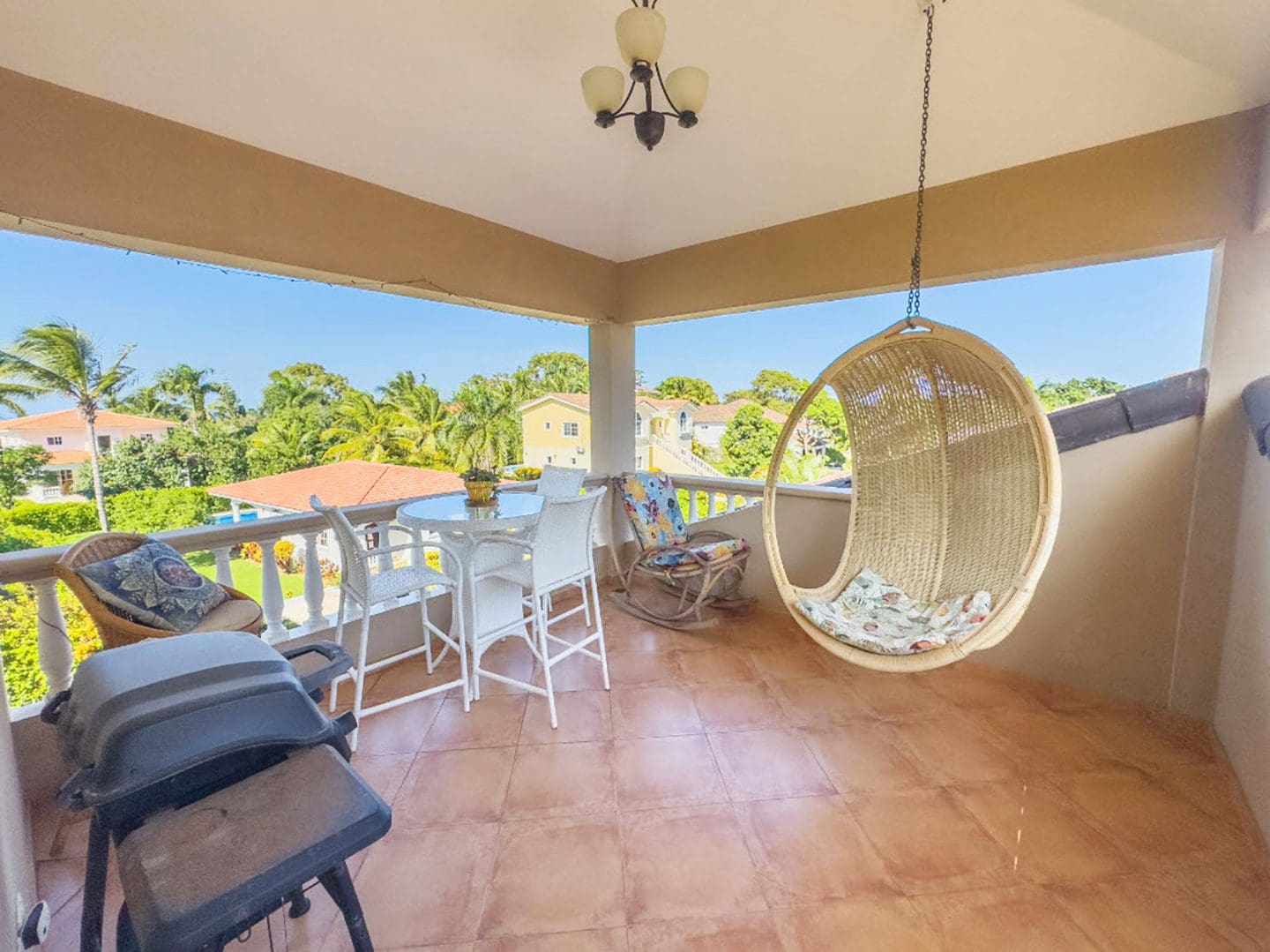 buyDRproperty Balcony of a Hispaniola Two Unit Villa with seating, hanging chair, and grill. Sosua Real Estate