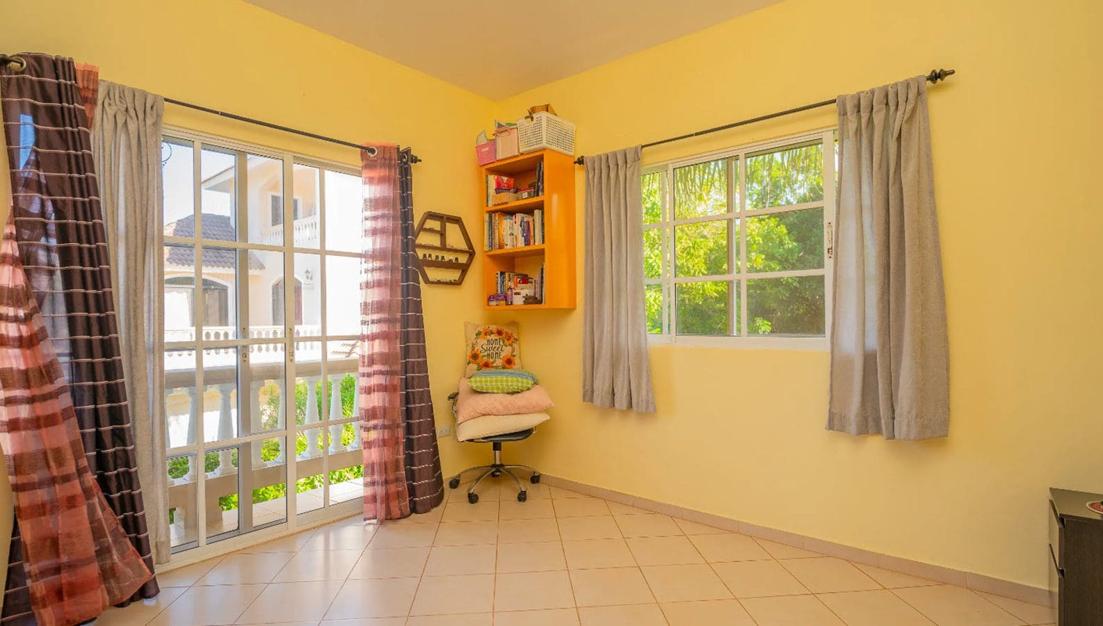 buyDRproperty Bright yellow room with a window, curtains, and a bookshelf in a residential Hispaniola Two Unit Villa. Sosua Real Estate