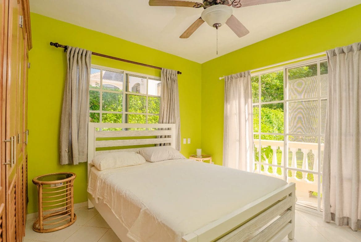 buyDRproperty Bedroom in Hispaniola Two Unit Villa with bright green walls and white bed. Sosua Real Estate