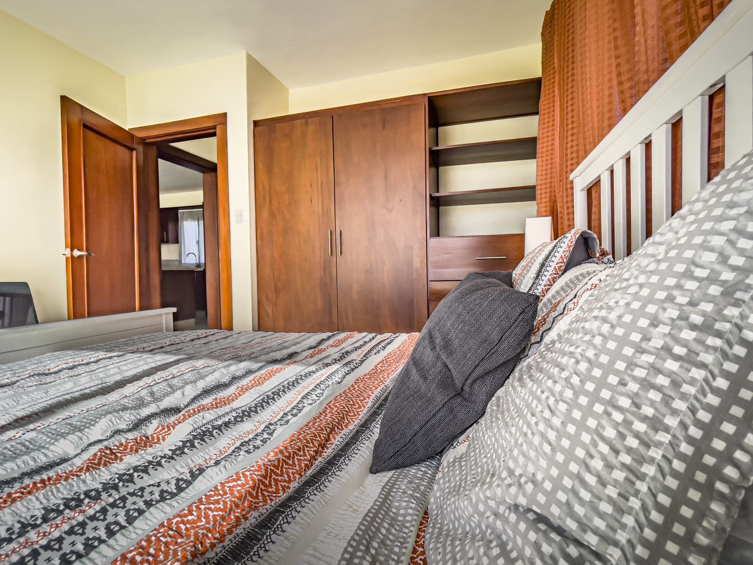 buyDRproperty Bedroom in a 2 Bedroom Villa For Sale, featuring a bed with patterned bedding and a large wardrobe. Sosua Real Estate