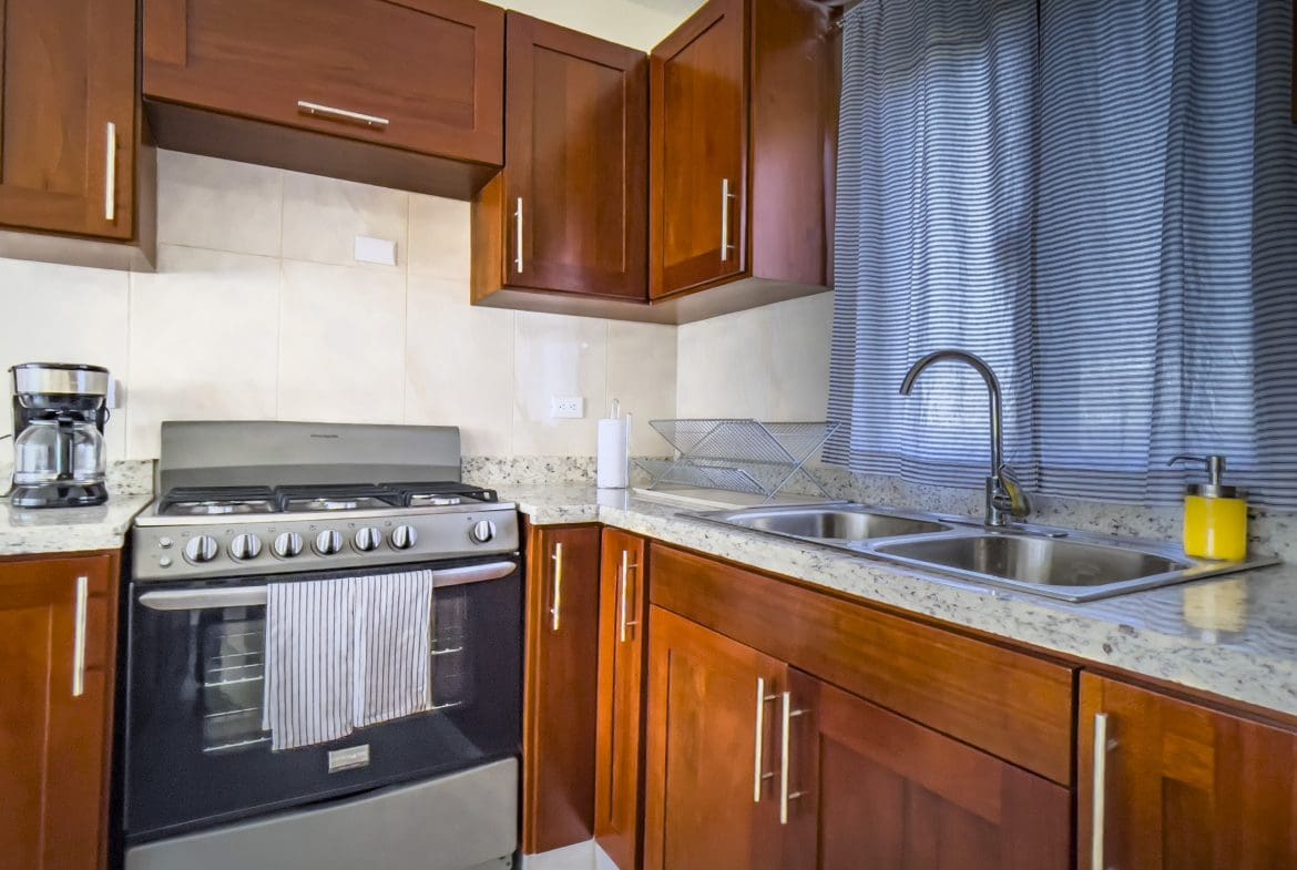 buyDRproperty Kitchen in a 2 Bedroom Villa For Sale, featuring wooden cabinets and a stove. Sosua Real Estate
