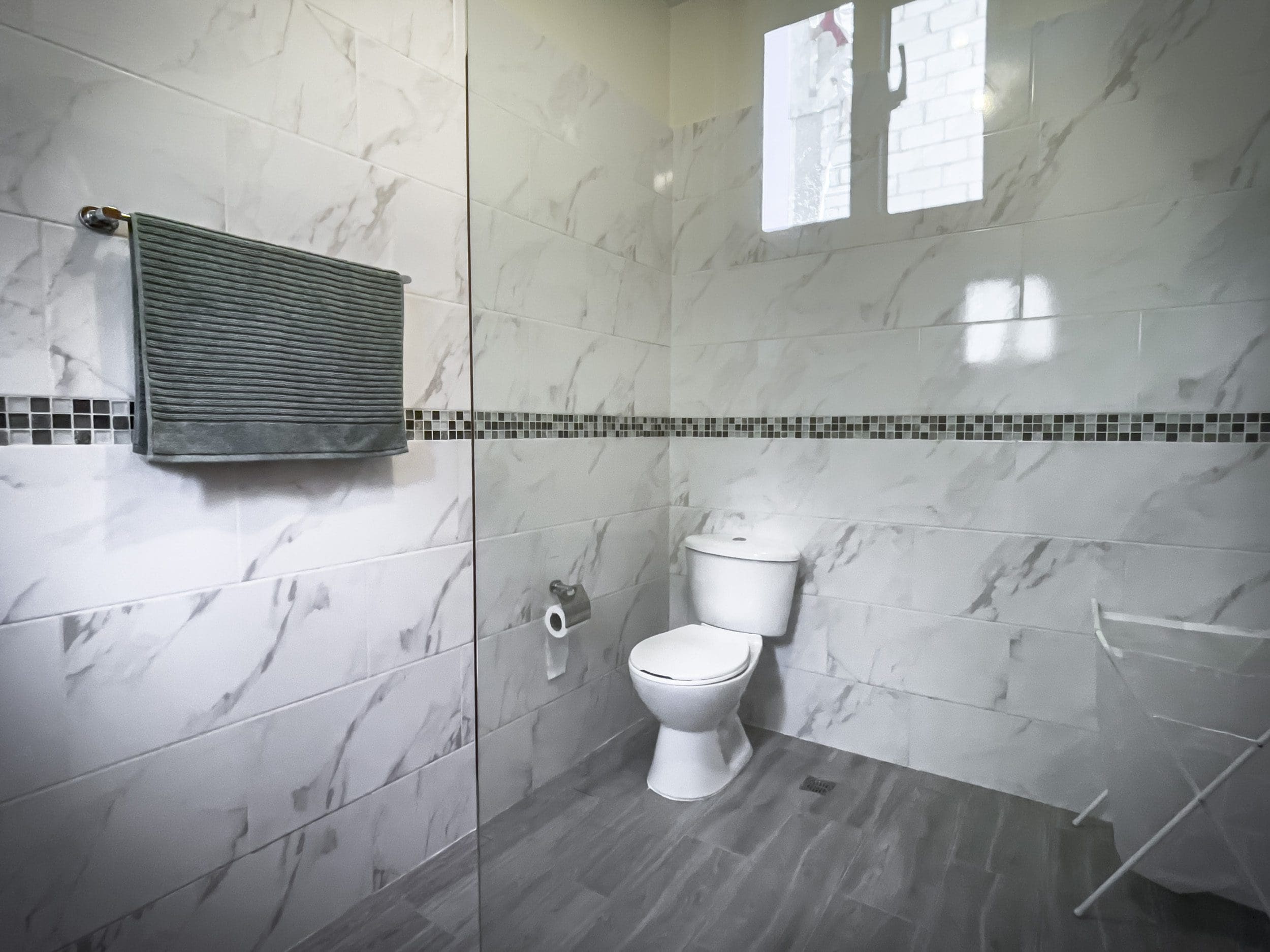 buyDRproperty Modern bathroom with white marble tiles and a toilet. 2 Bedroom Villa For Sale. Sosua Real Estate