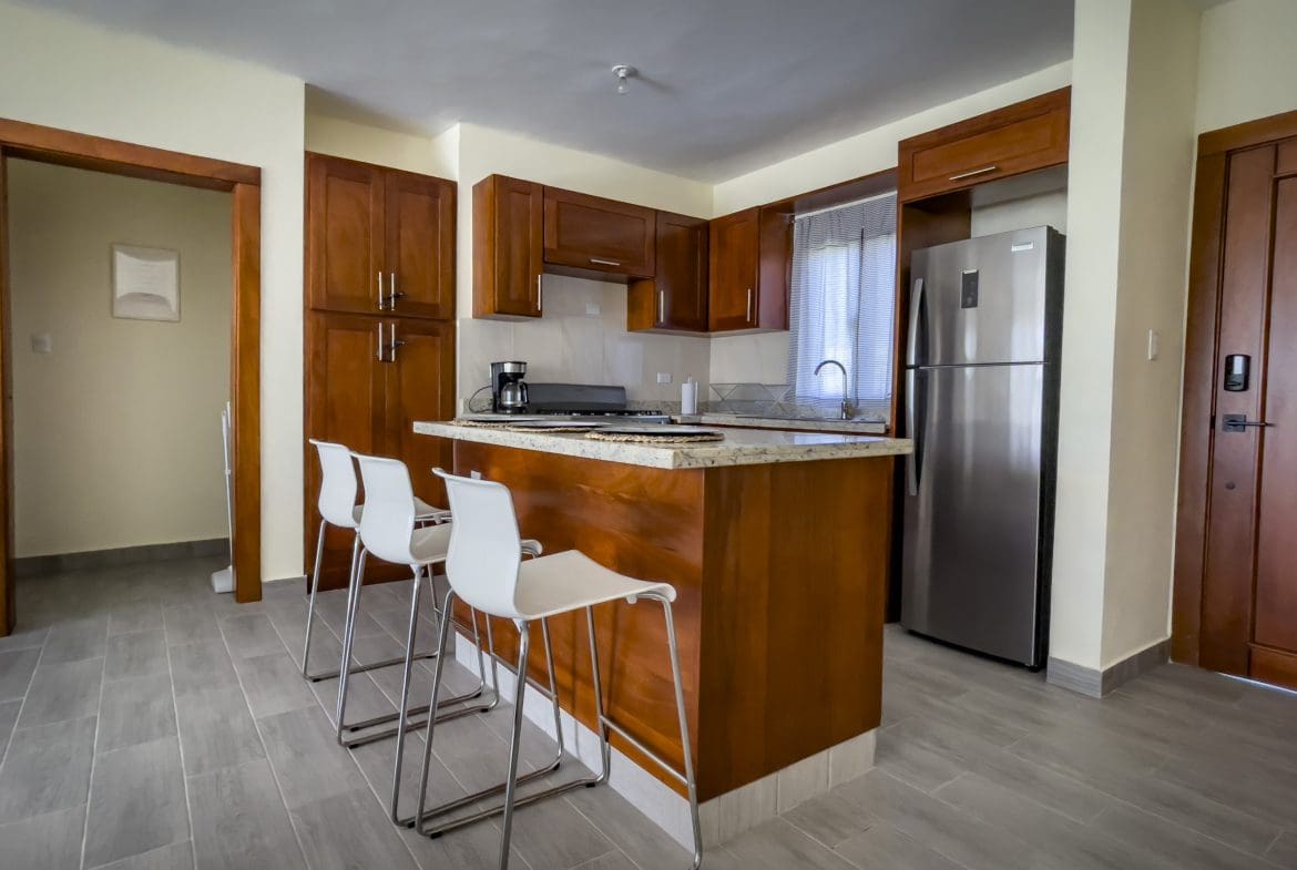 buyDRproperty Modern kitchen in a 2 bedroom villa for sale. Features wood cabinets, stainless steel appliances, and breakfast bar. Sosua Real Estate