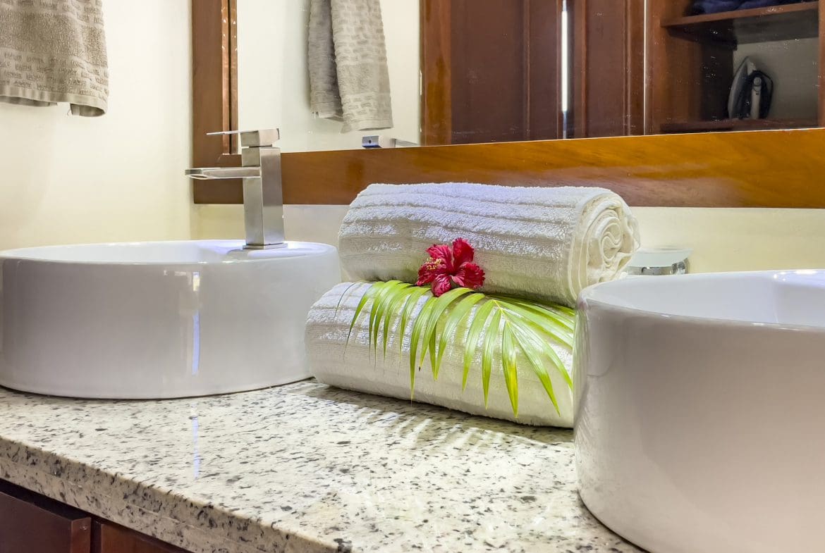 buyDRproperty Bathroom vanity with white sinks, towels, and a red flower. 2 Bedroom Villa For Sale. Sosua Real Estate