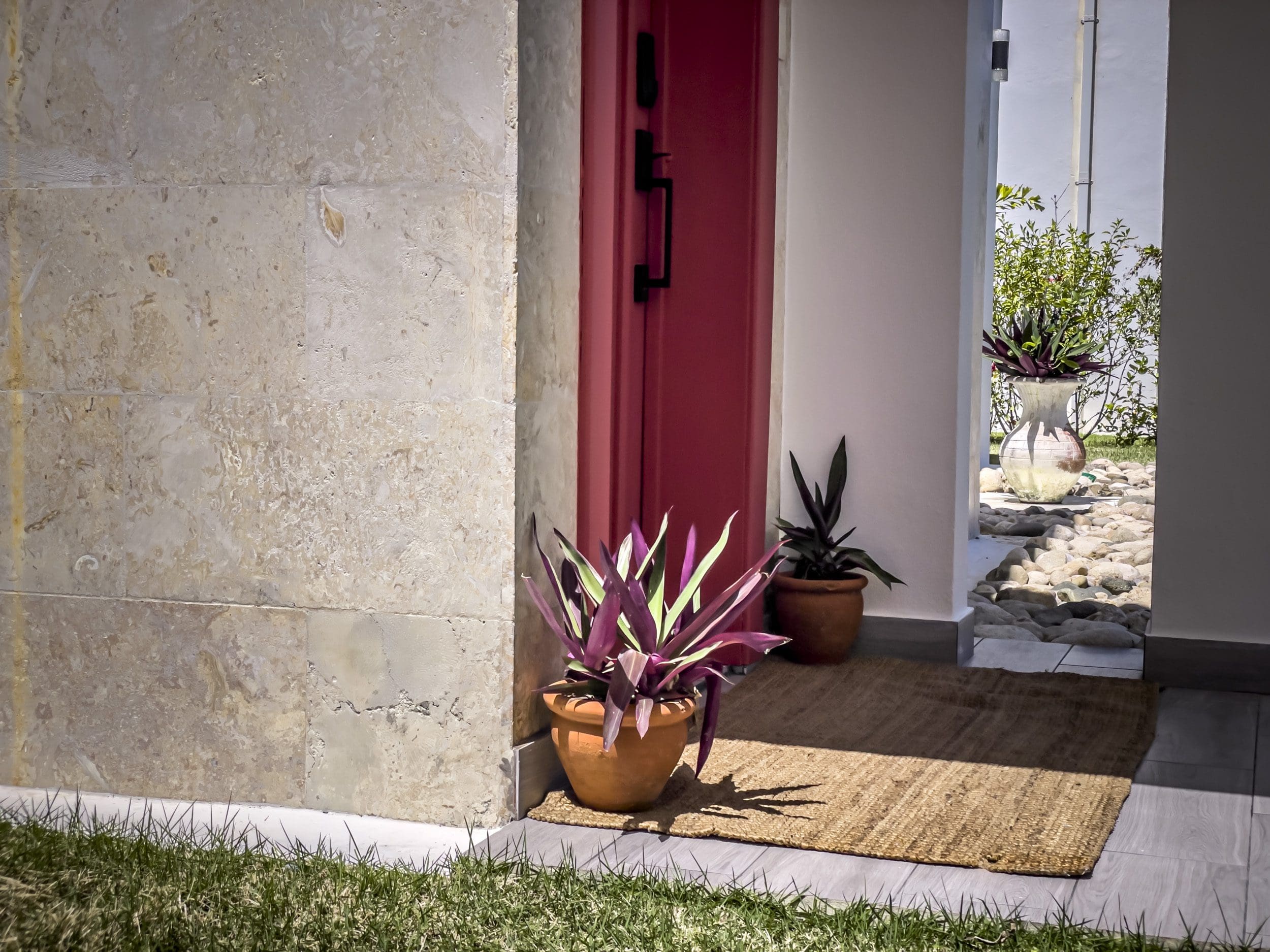 buyDRproperty Entrance of a 2 bedroom villa for sale with colorful plants and red door. Sosua Real Estate