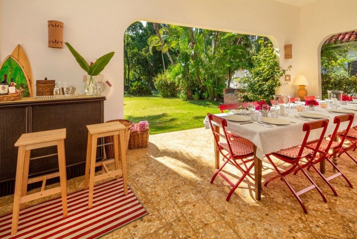 buyDRproperty Outdoor dining area at Villa Blanca, with a table set for a meal and a beautiful garden view. Sosua Real Estate