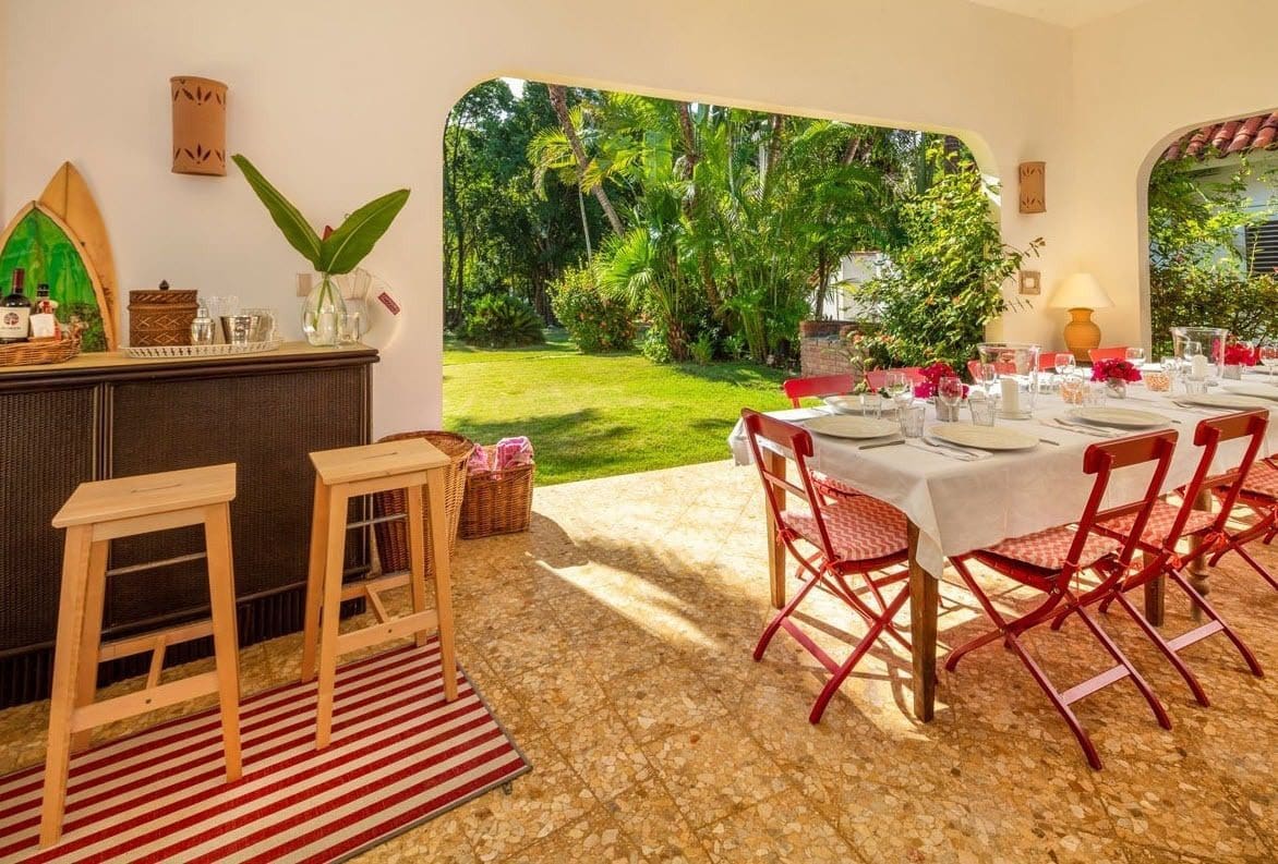 buyDRproperty Outdoor dining area at Villa Blanca, with a table set for a meal and a beautiful garden view. Sosua Real Estate