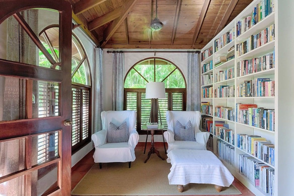 buyDRproperty Cozy reading nook in a Sea Horse Ranch Villa, with armchairs, bookshelf, and arched window. Sosua Real Estate