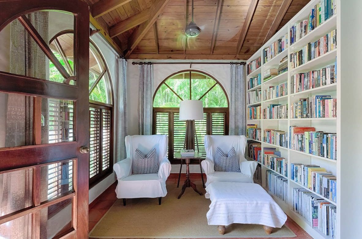 buyDRproperty Cozy reading nook in a Sea Horse Ranch Villa, with armchairs, bookshelf, and arched window. Sosua Real Estate