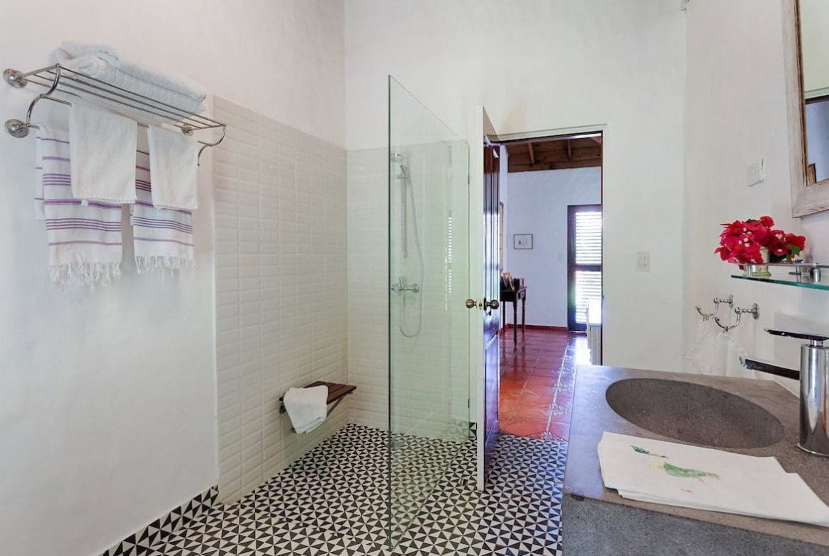 buyDRproperty Bathroom with white tiled walls and black and white patterned floor in a Sea Horse Ranch Villa. Sosua Real Estate