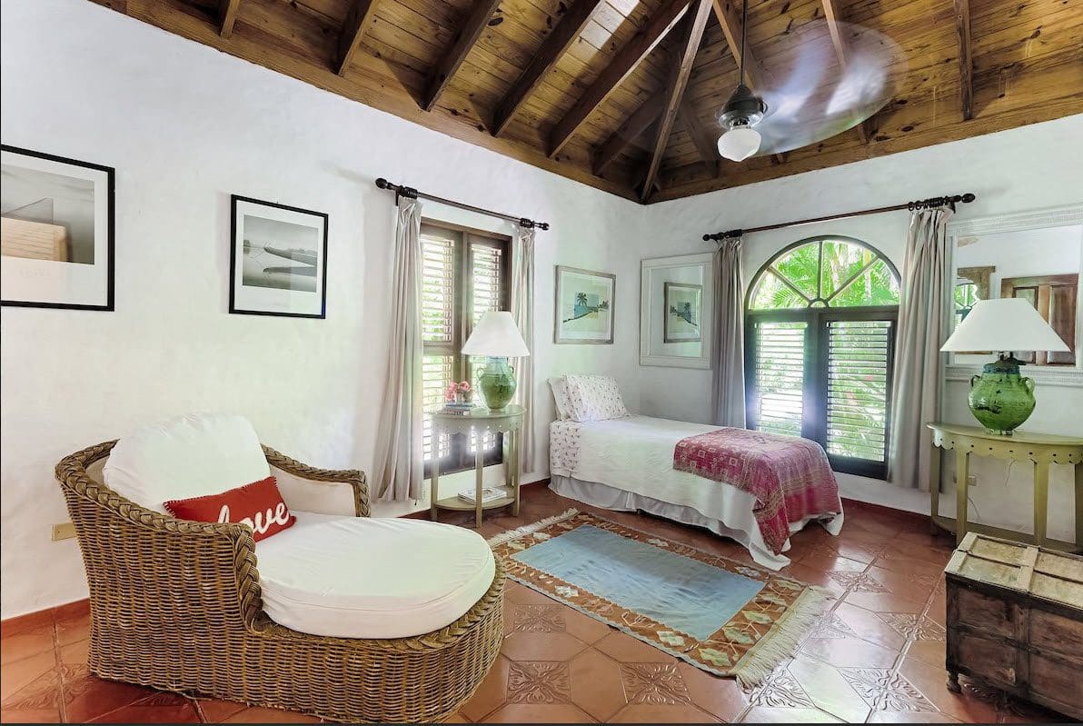 buyDRproperty Cozy bedroom at Sea Horse Ranch Villa with wicker chaise lounge and arched window. Sosua Real Estate