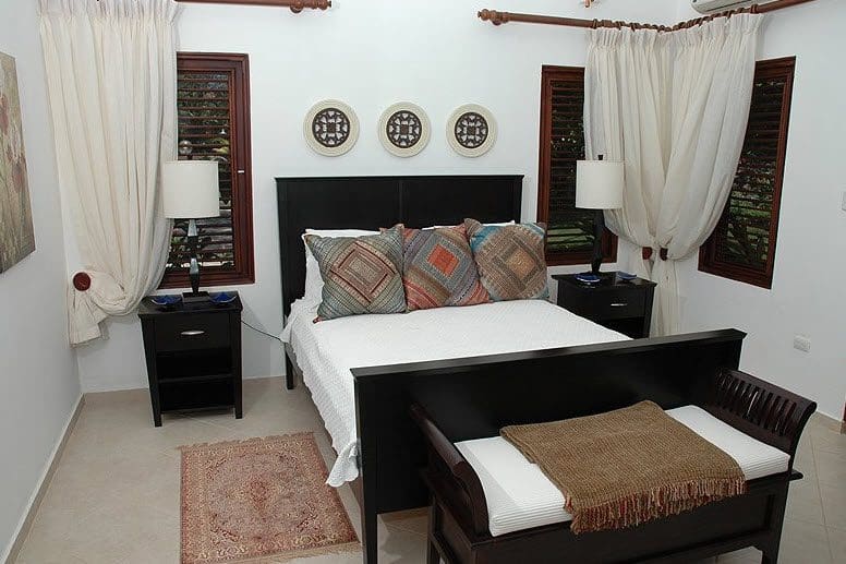 buyDRproperty Bedroom in Beautiful VILLA BRILLANTE with dark wood bed, white bedding, and decorative pillows. Sosua Real Estate